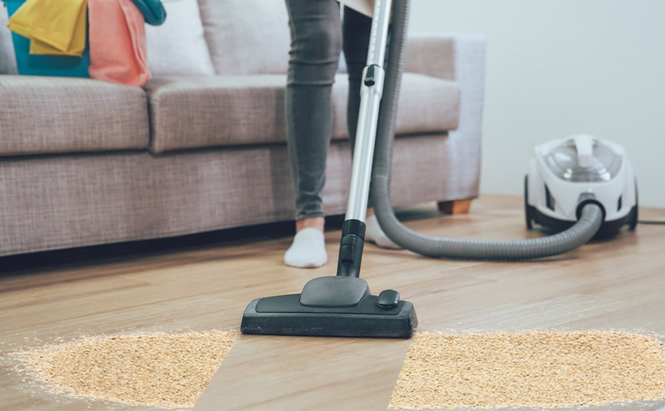 cleaner removing sand from vacation rental floor Emerald Coast